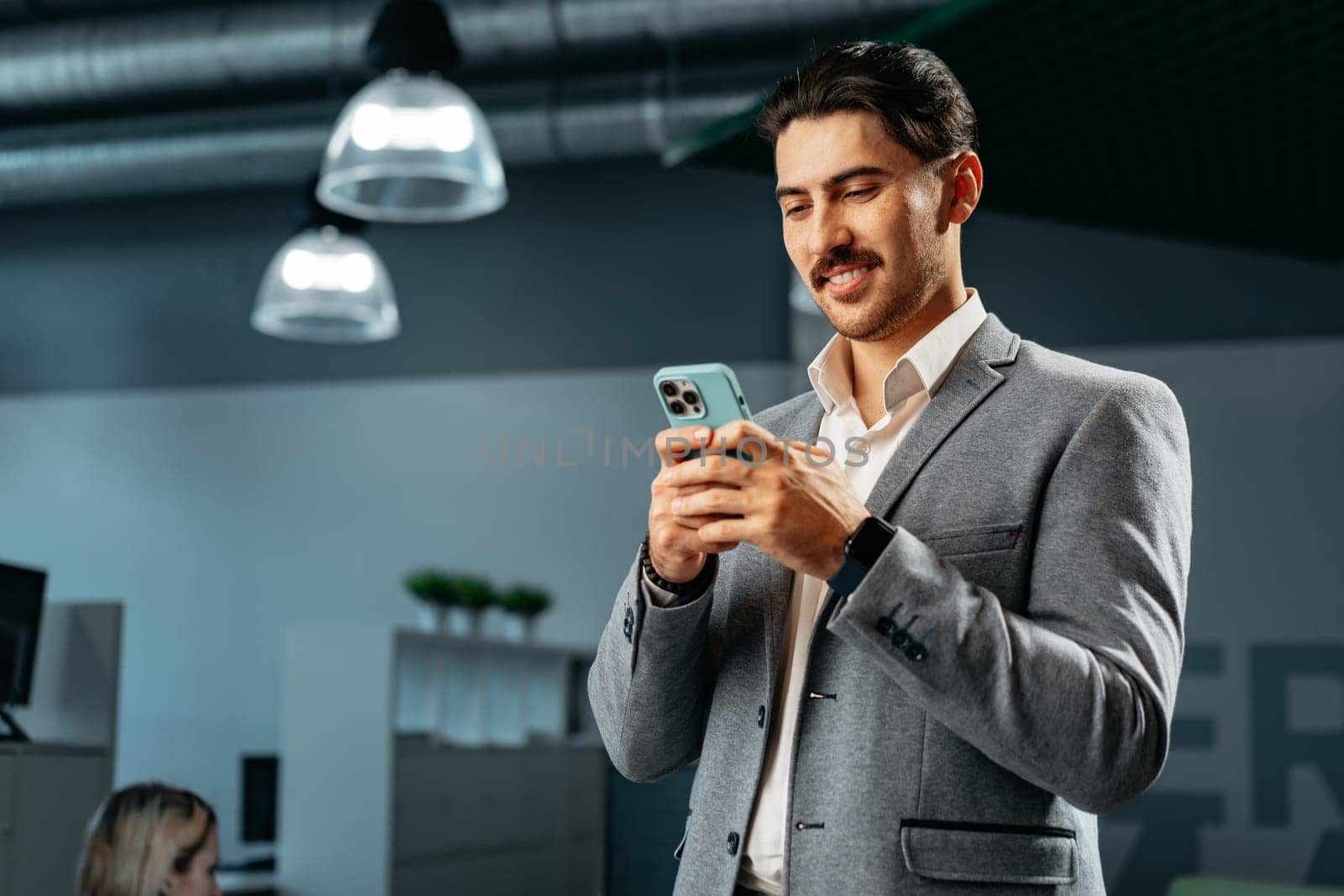 Handsome young arab man in formal wear using smartphone in office close up