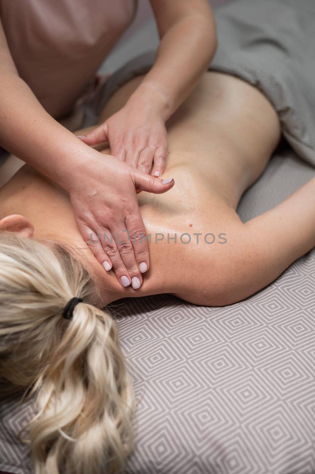 A woman undergoing a massage of the cervical-collar area. Vertical photo. by mrwed54