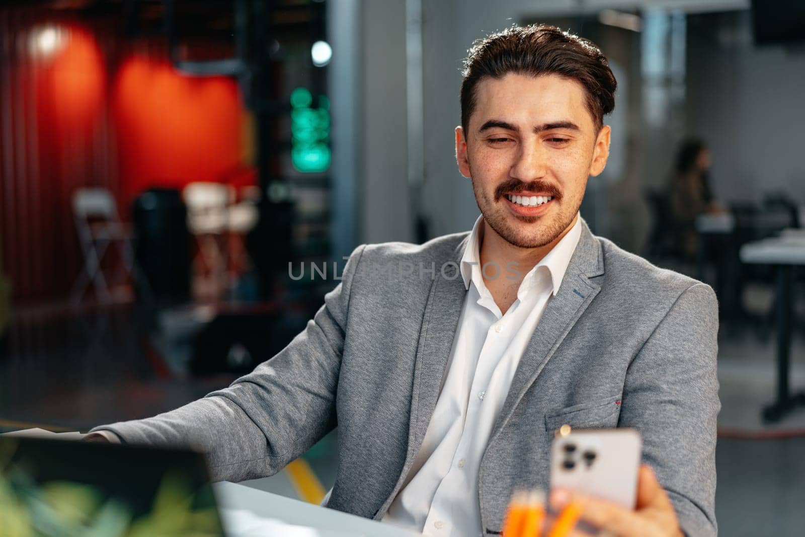 Businessman in formal wear using his smartphone while sitting at the working table close up