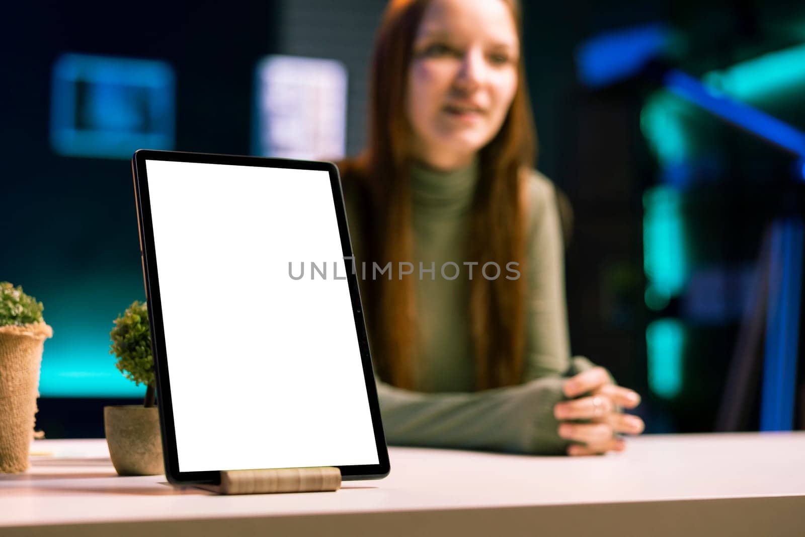 Focus on mockup tablet with gen Z teenager in blurry background doing review, comparing features. Close up shot of isolated screen portable device analyzed by influencer, filming online video
