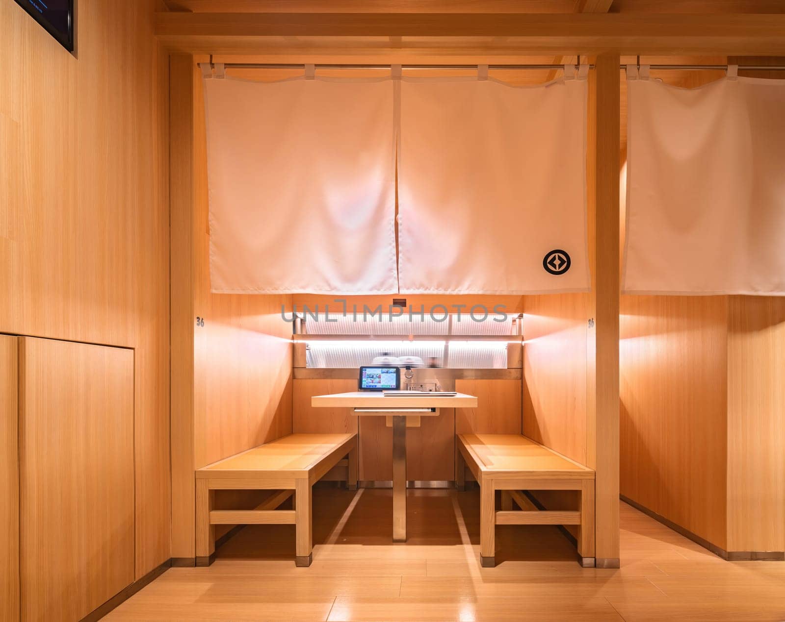 tokyo, ginza - may 14 2024: Kura Revolving Sushi Bar's modern wooden booths equipped with a digital menu displayed on a tablet and decorated in a Japanese style with traditional noren curtains.