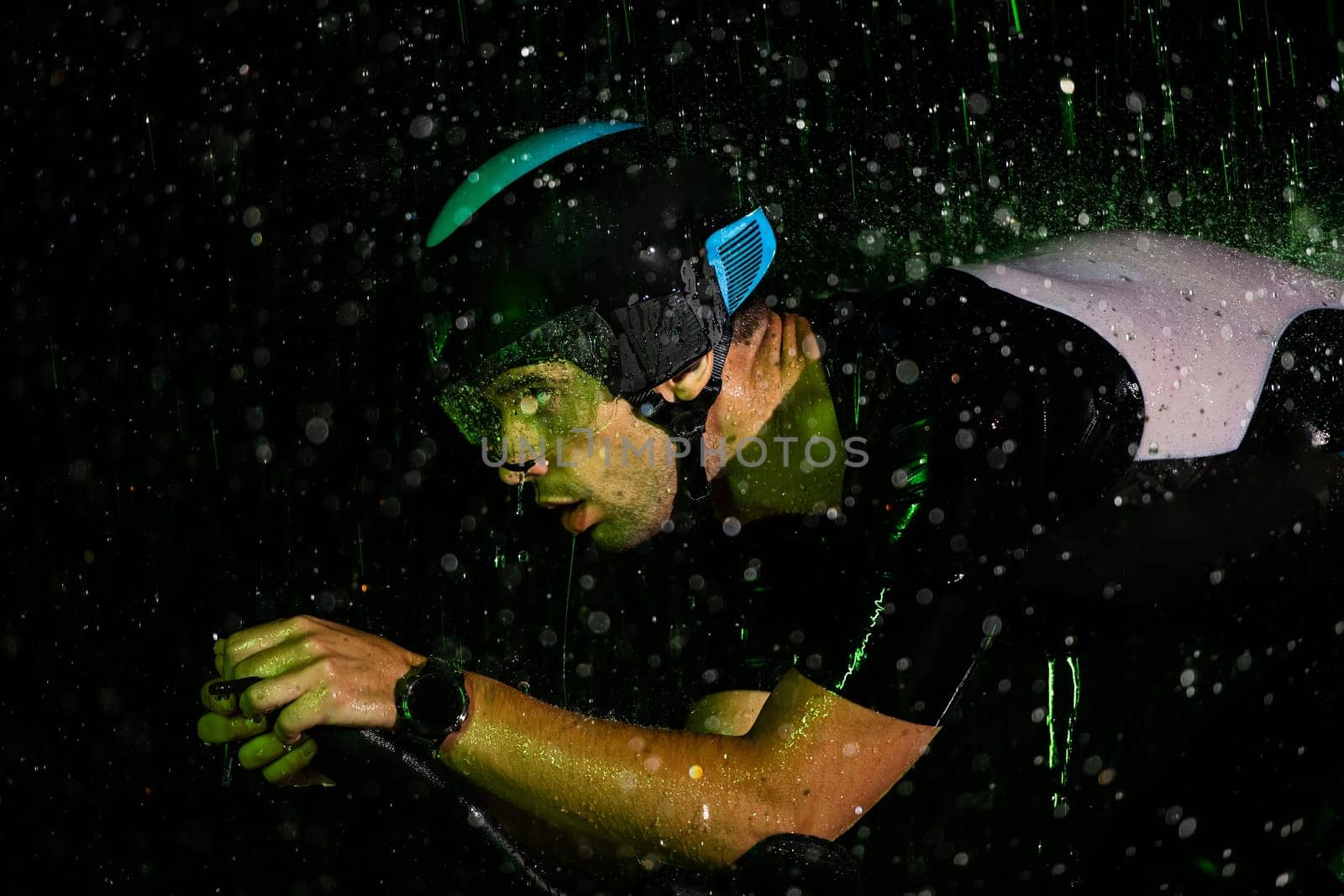 A triathlete braving the rain as he cycles through the night, preparing himself for the upcoming marathon by dotshock