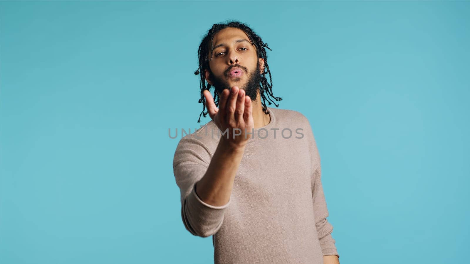 Man blowing kisses to camera, being flirty, studio background by DCStudio