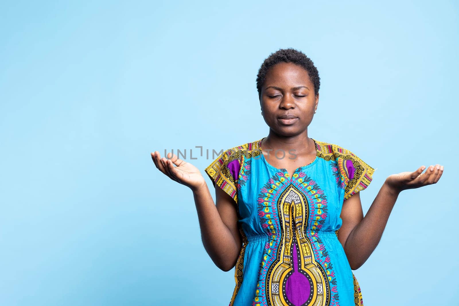 Female model praying to Jesus Christ for a miracle, expressing her belief in Christianity and the Lord over blue background. Religious pious woman saying a prayer, worshipping God.