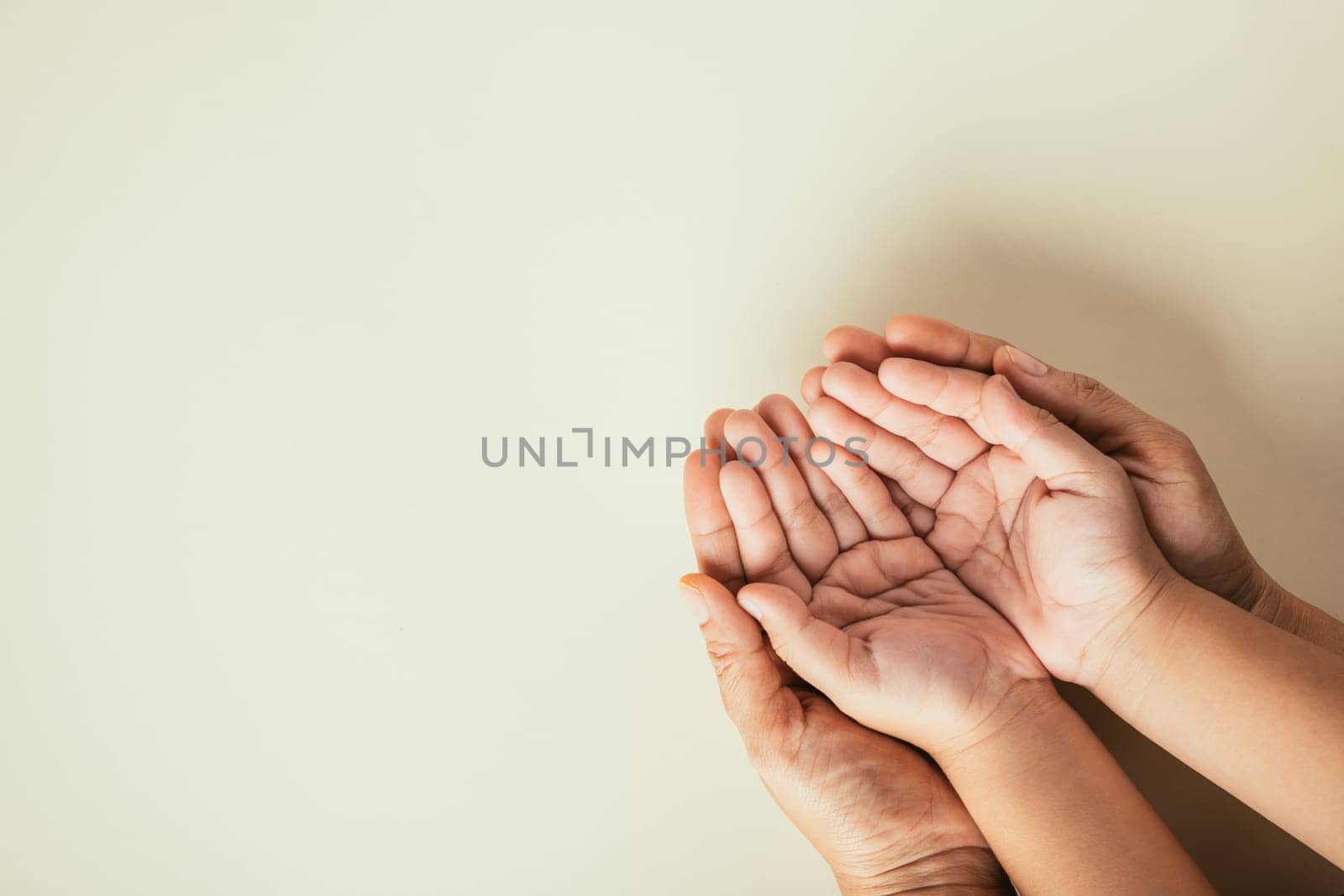 Top view of parents and kid holding empty hands on color background. Celebrating Family Day portraying togetherness support and family heritage.