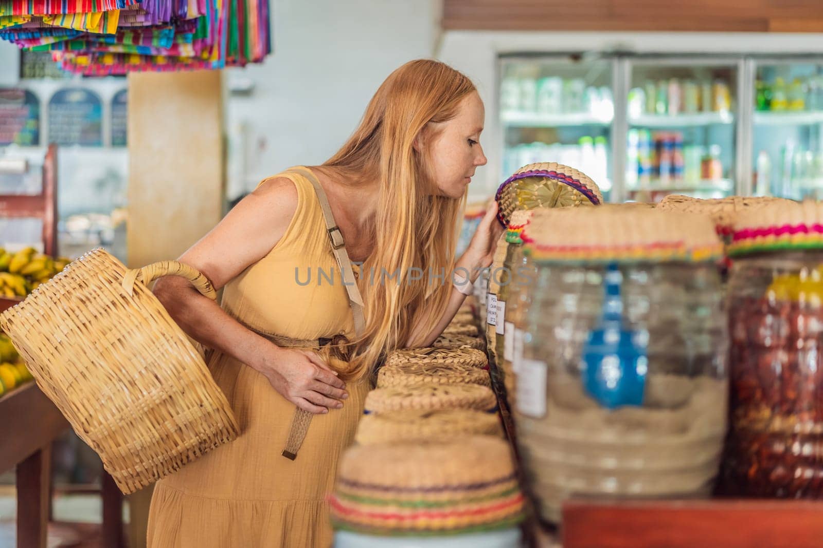 In a grocery store, a pregnant woman stands by a fruit stand, surrounded by various natural foods. She is in a public space where the local market offers whole foods for trade Pregnant woman buying organic vegetables and fruits at Mexican style farmers market