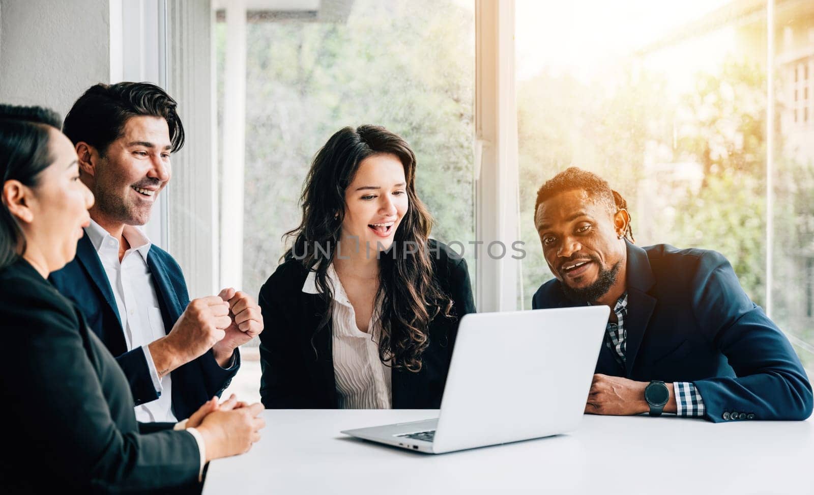 Diverse colleagues, both men and women, collaborate in a meeting room using a laptop. Their teamwork, diversity, and cooperation are palpable as they discuss, plan, and strategize for success. by Sorapop