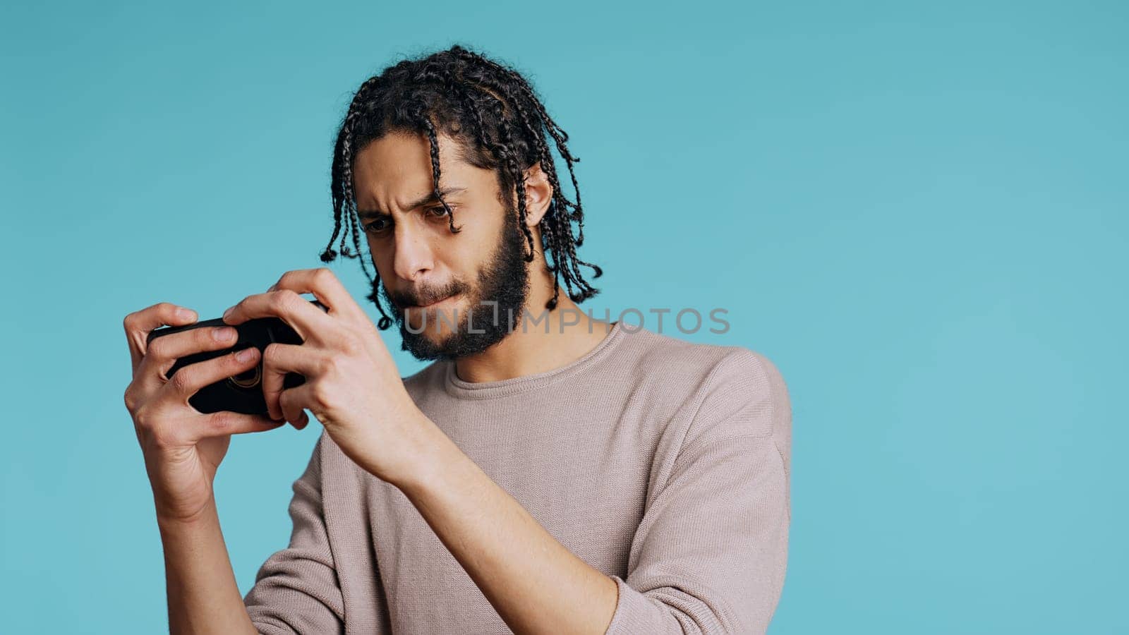 Happy man with disability in wheelchair playing videogames on cellphone, celebrating victory. Cheerful gamer enjoying game on phone, excited about win, studio background, camera B