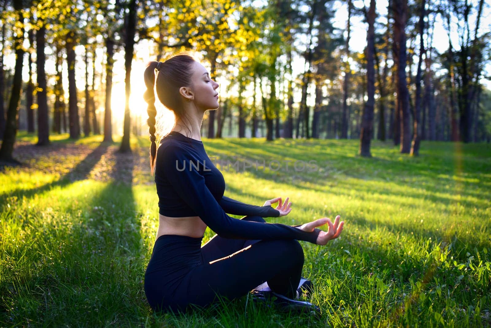 A young woman meditates in a tranquil forest at sunrise, surrounded by natures beauty, practicing mindfulness