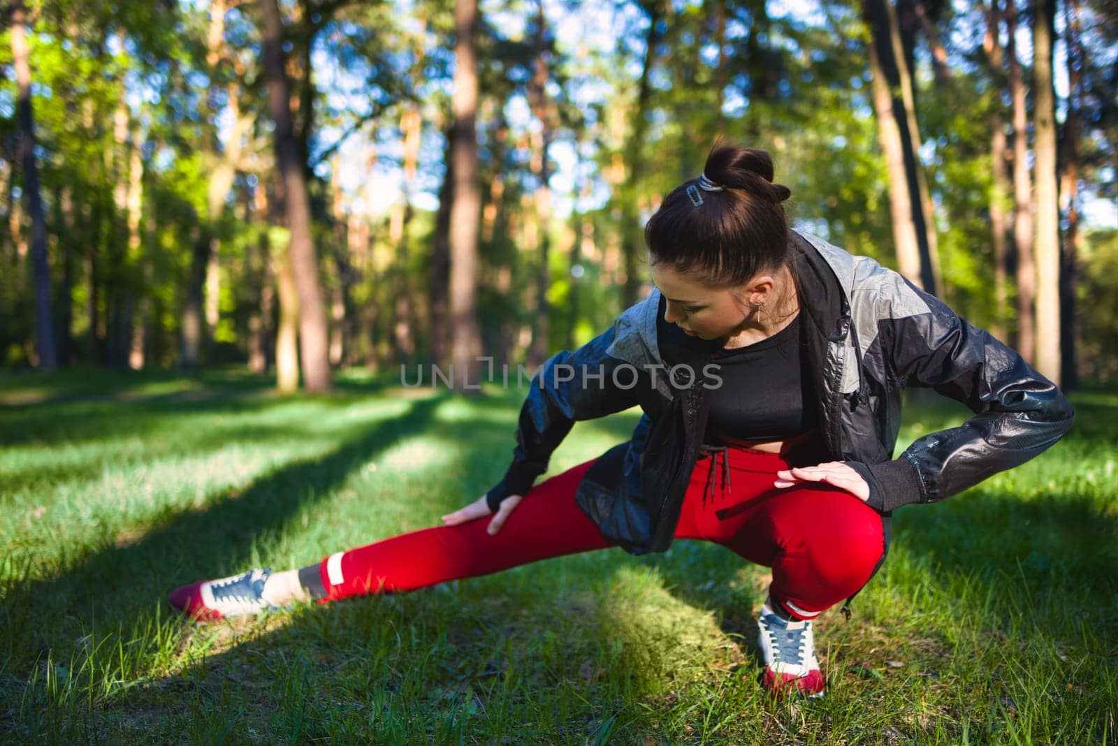 Young woman in tracksuit doing stretching in the woods in early spring