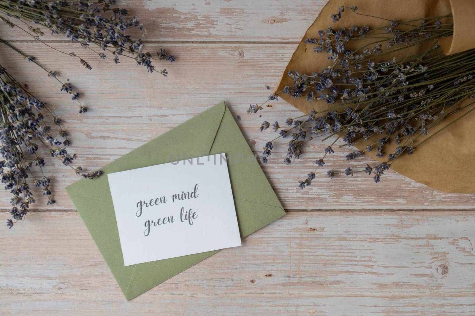 GREEN MIND GREEN LIFE text on supportive message paper note reminder from green envelope. Flat lay composition dry lavender flowers. Concept of eco-friendly lifestyle, environmental recyclable reusable low waste living. Top view