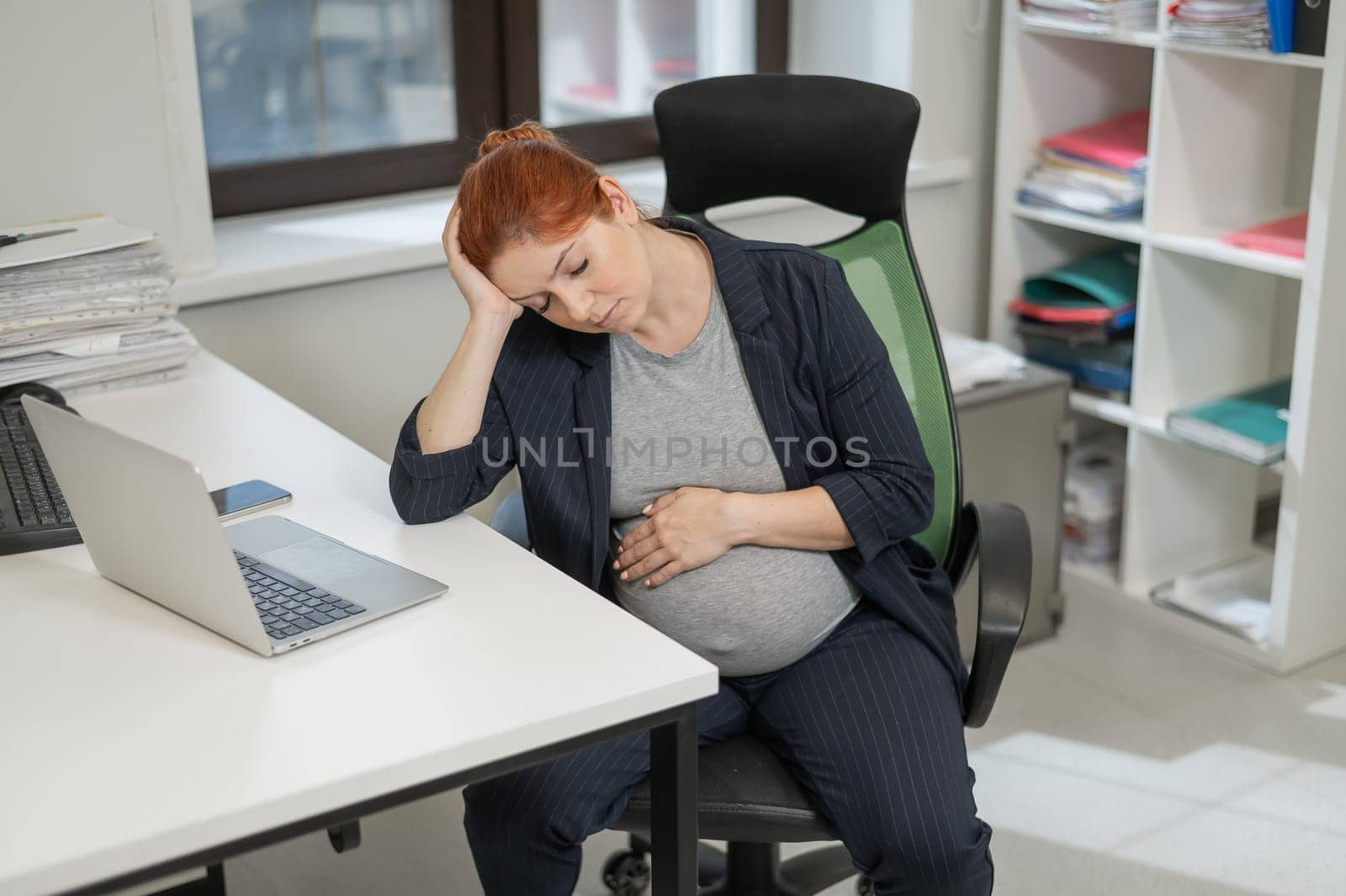 Pregnant woman sleeping at her desk in the office