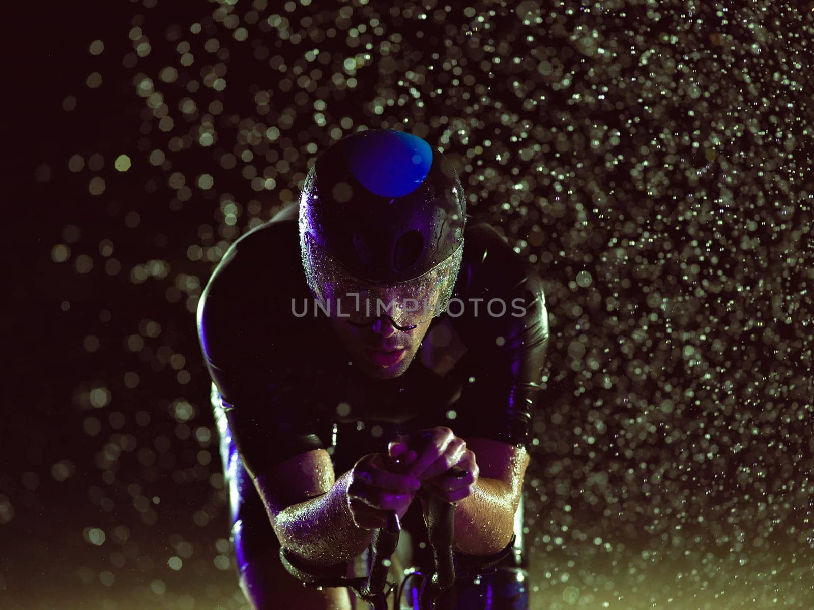 A triathlete braving the rain as he cycles through the night, preparing himself for the upcoming marathon by dotshock