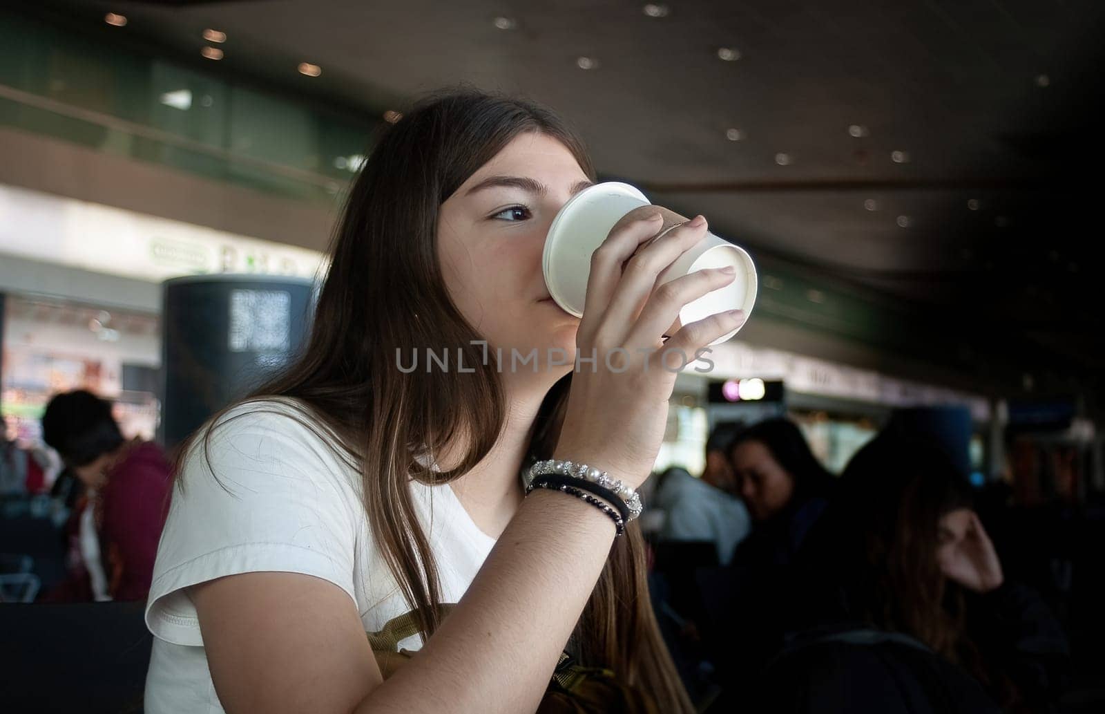 Young woman having coffe and looking through airport window by VeroDibe