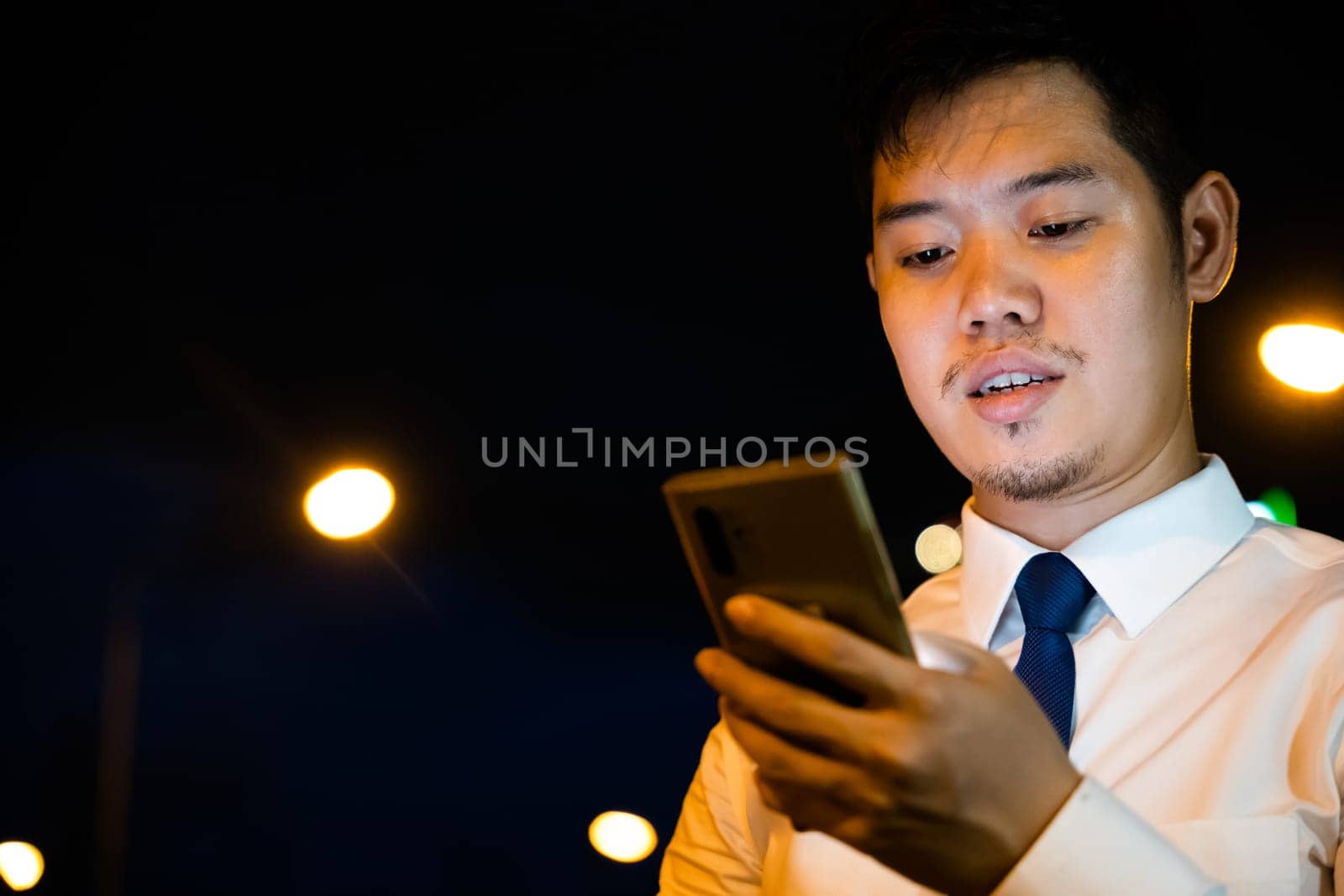Stylish man suit using smartphone in neon-lit city street. Engaged in social media texting online shopping. Modern businessman communication success in night.