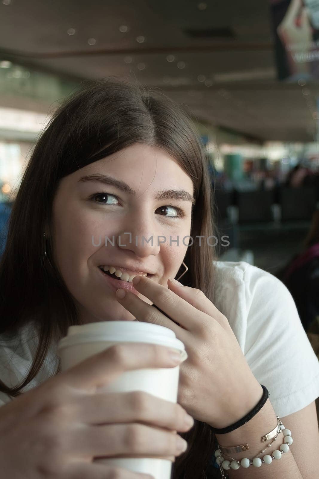 Young woman drinking coffee during a stopover at an international airport by VeroDibe