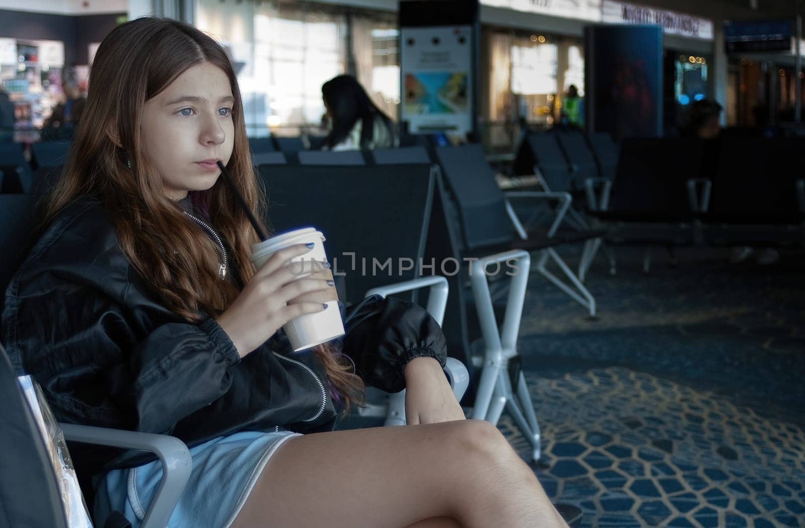 Young girl looks out of the airport window as she waits for her plane to depart.