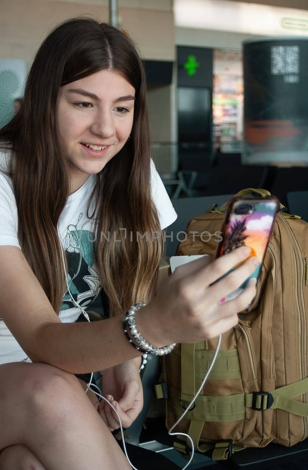 Young woman making video call with smart phone while waiting for her plane to depart