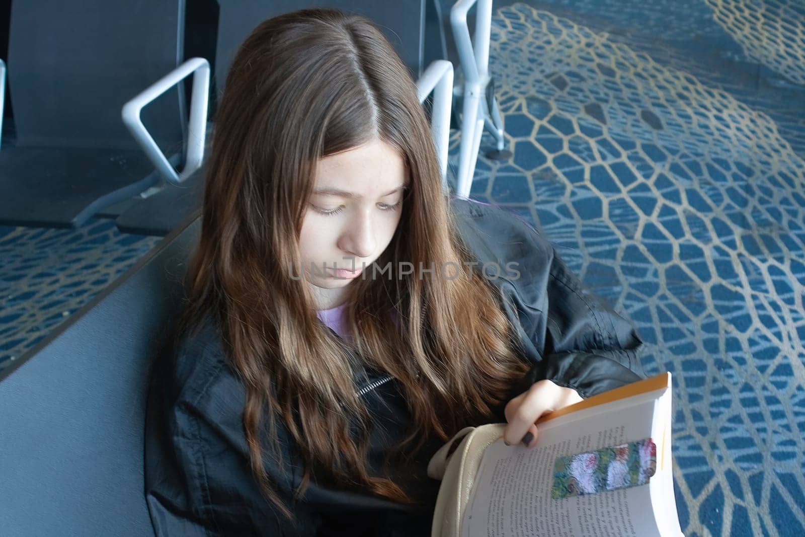 Girl reads as she waits for her plane to depart.Close-up photo by VeroDibe