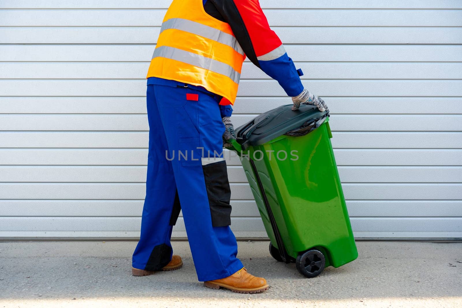 Janitor takes garbage out of trash container outdoors in the street