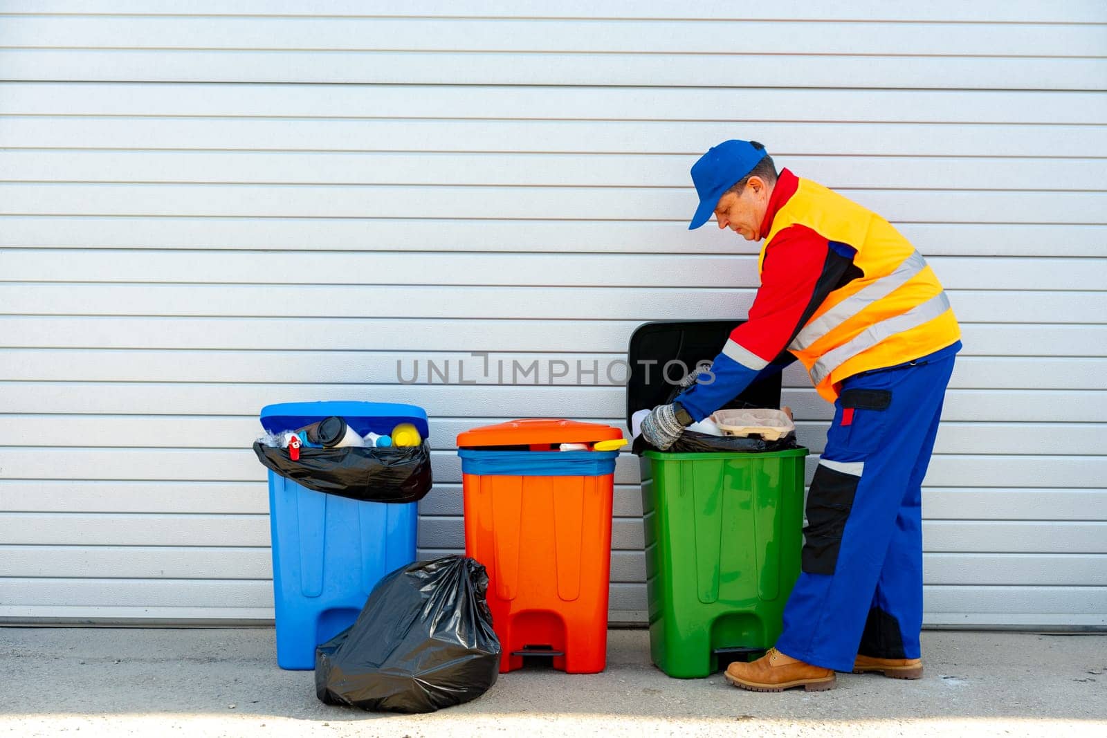 Janitor takes garbage out of trash container outdoors in the street