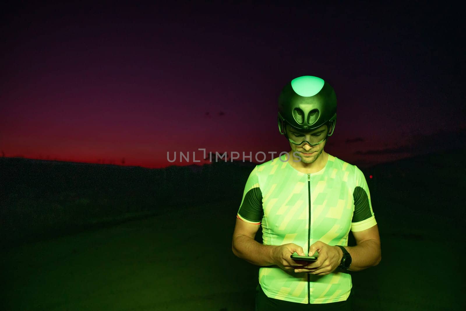 A triathlete using a smartphone while taking a break from a hard night's cycling training. High quality photo