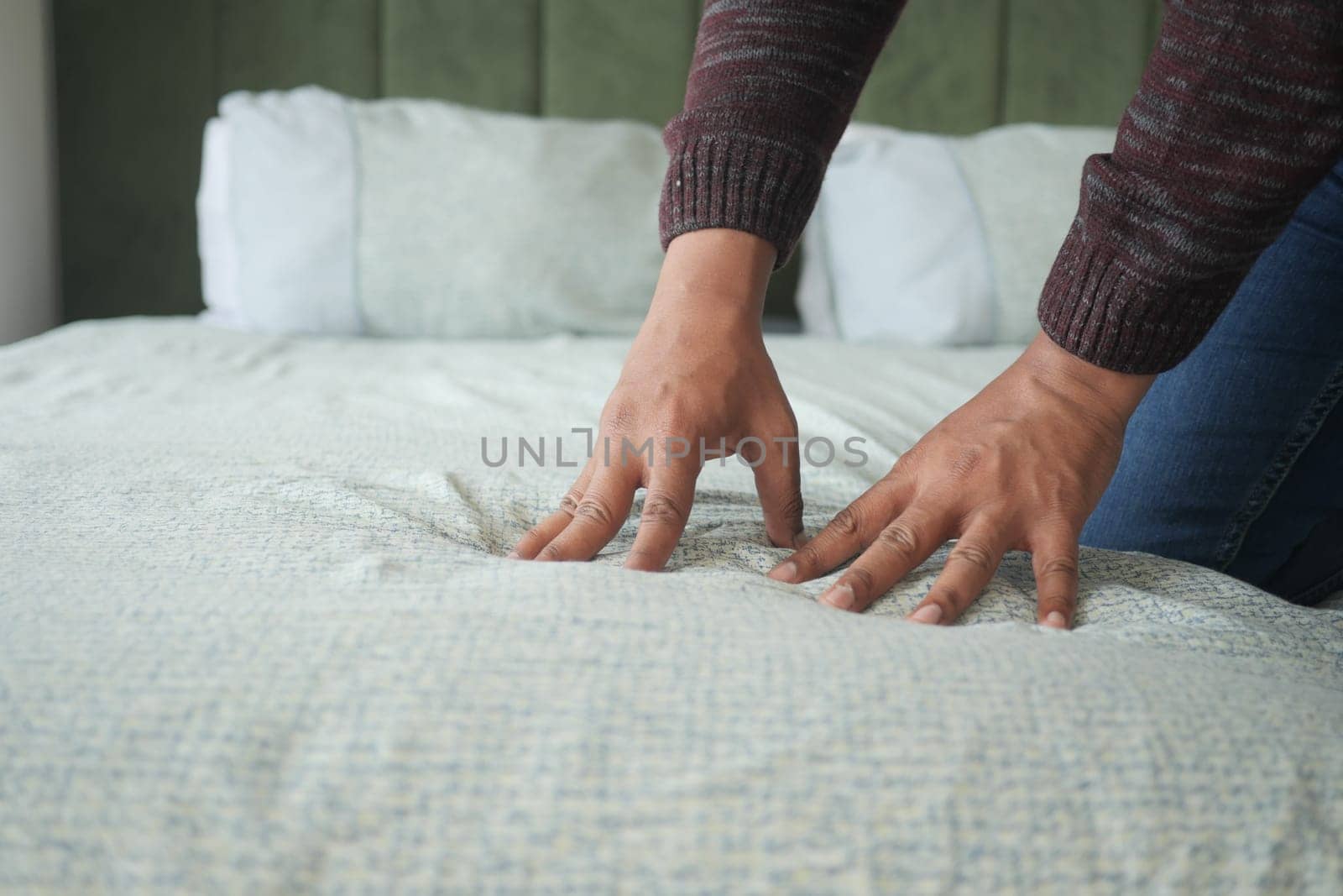 man hand touching and pressing orthopedic mattress on bed