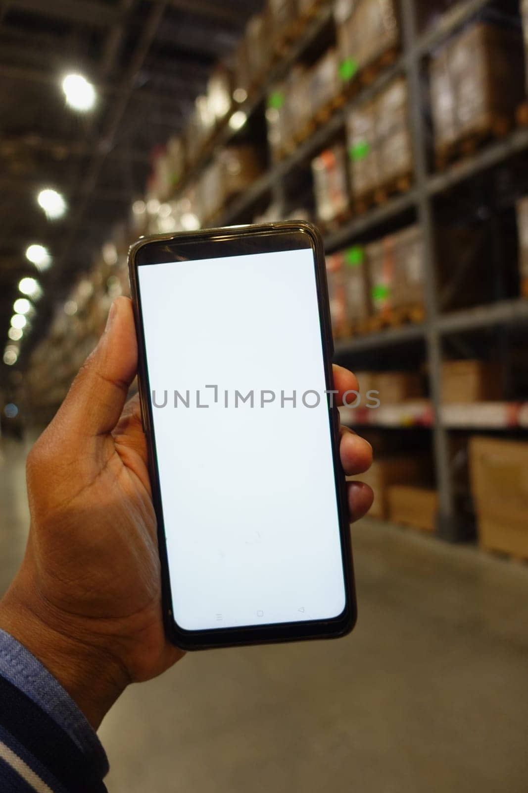 business owner holding phone mock up in warehouse