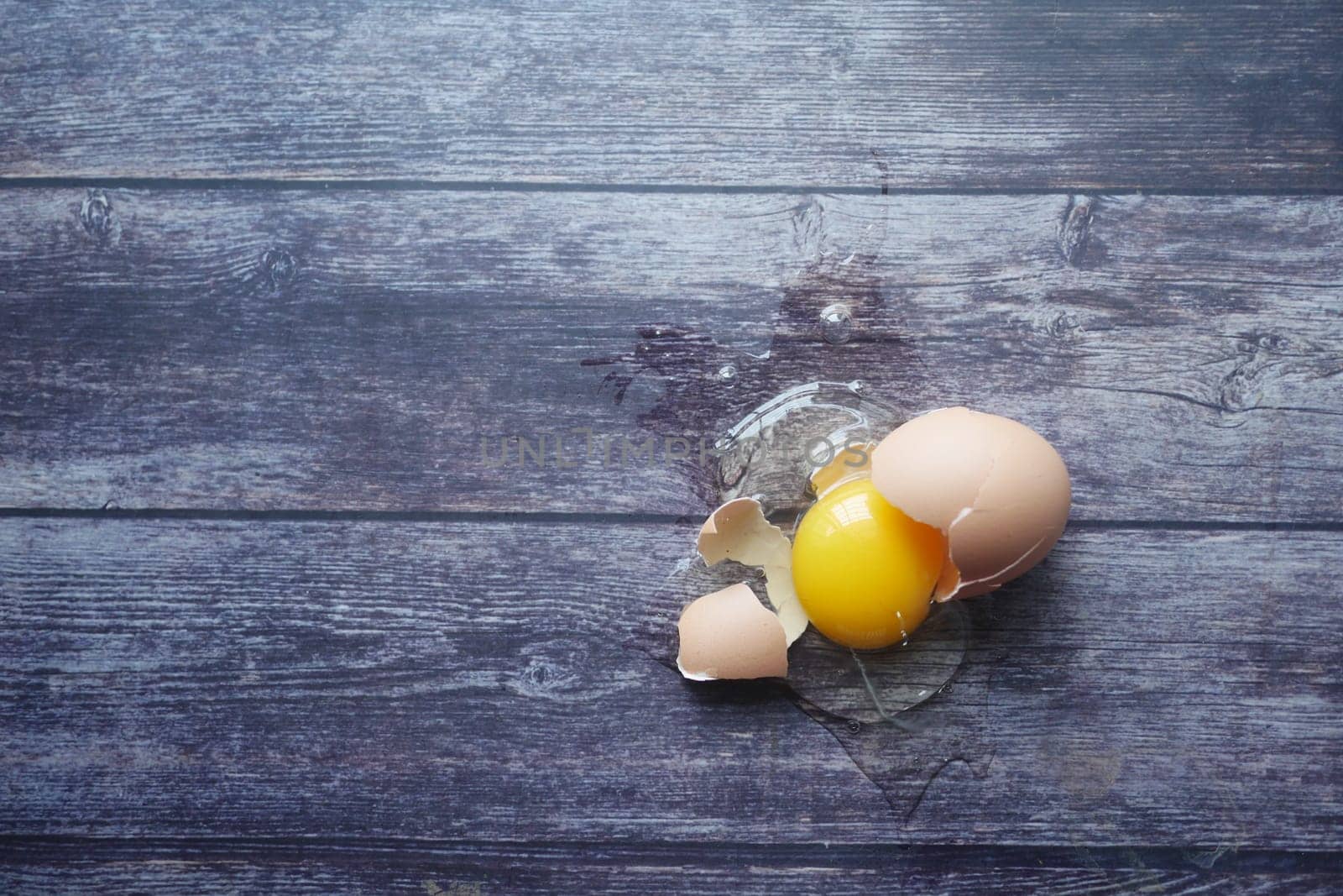 Fresh broken egg on wooden table .