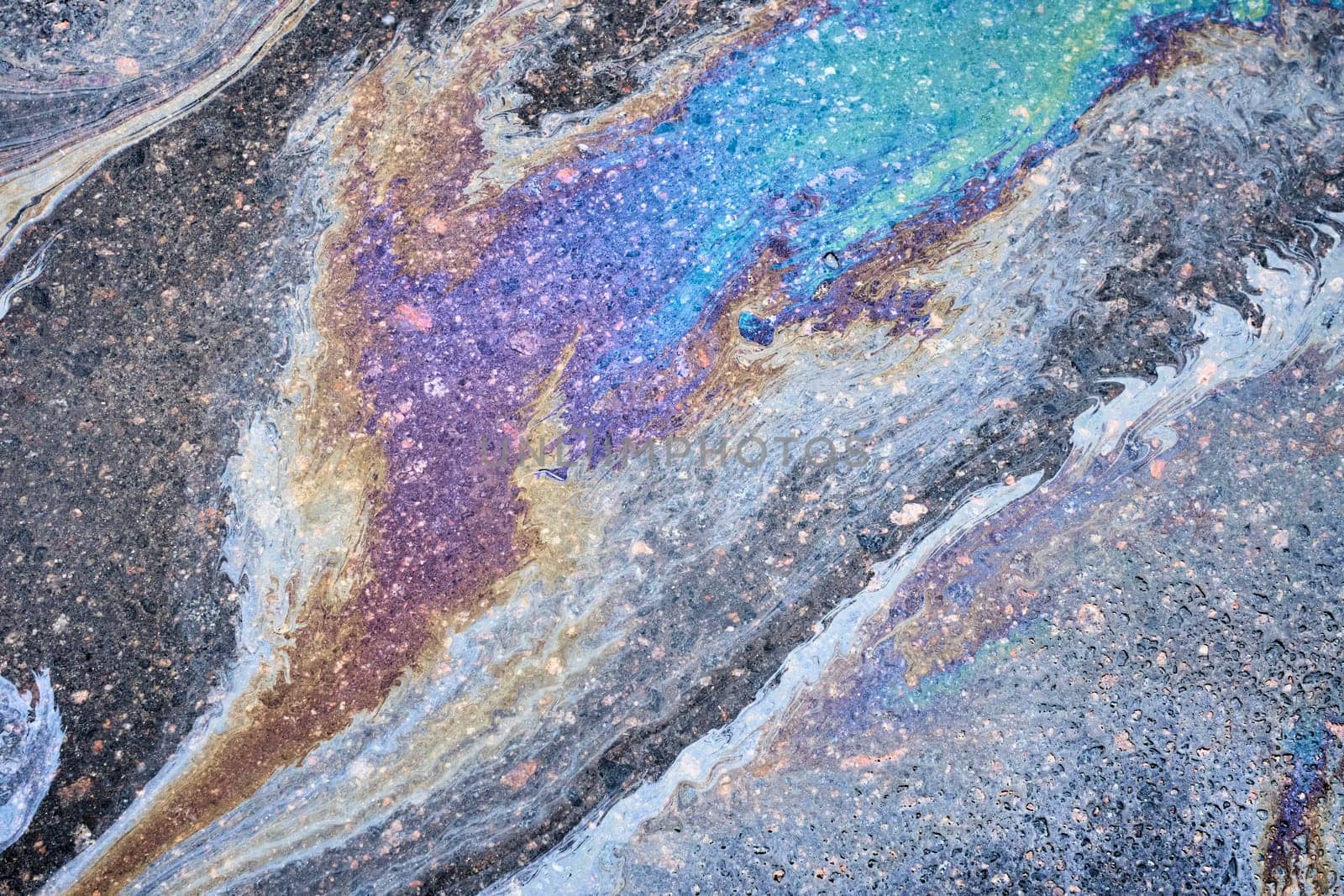 A car's oil and gas stains mark the surface of the parking asphalt.