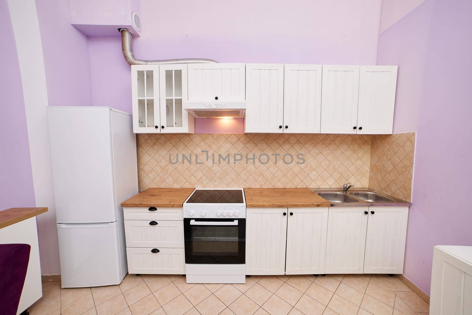 Purple kitchen with white cabinets, stove and refrigerator. High quality photo
