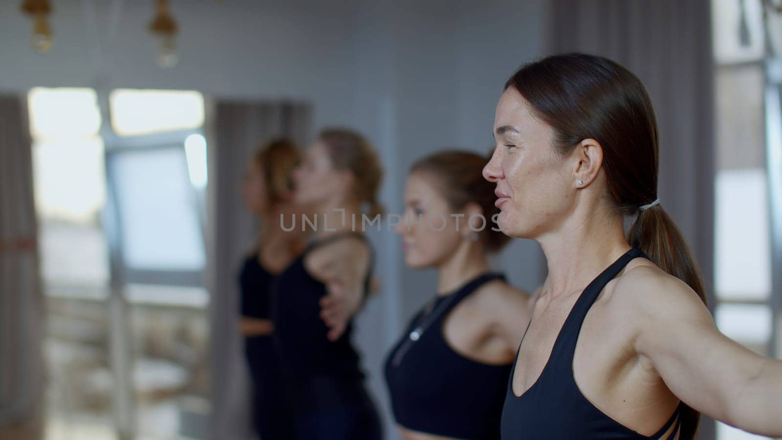 Group of sportive people during a gym training with a coach. Media. Girls group of athletes swinging hands before starting a workout yoga session