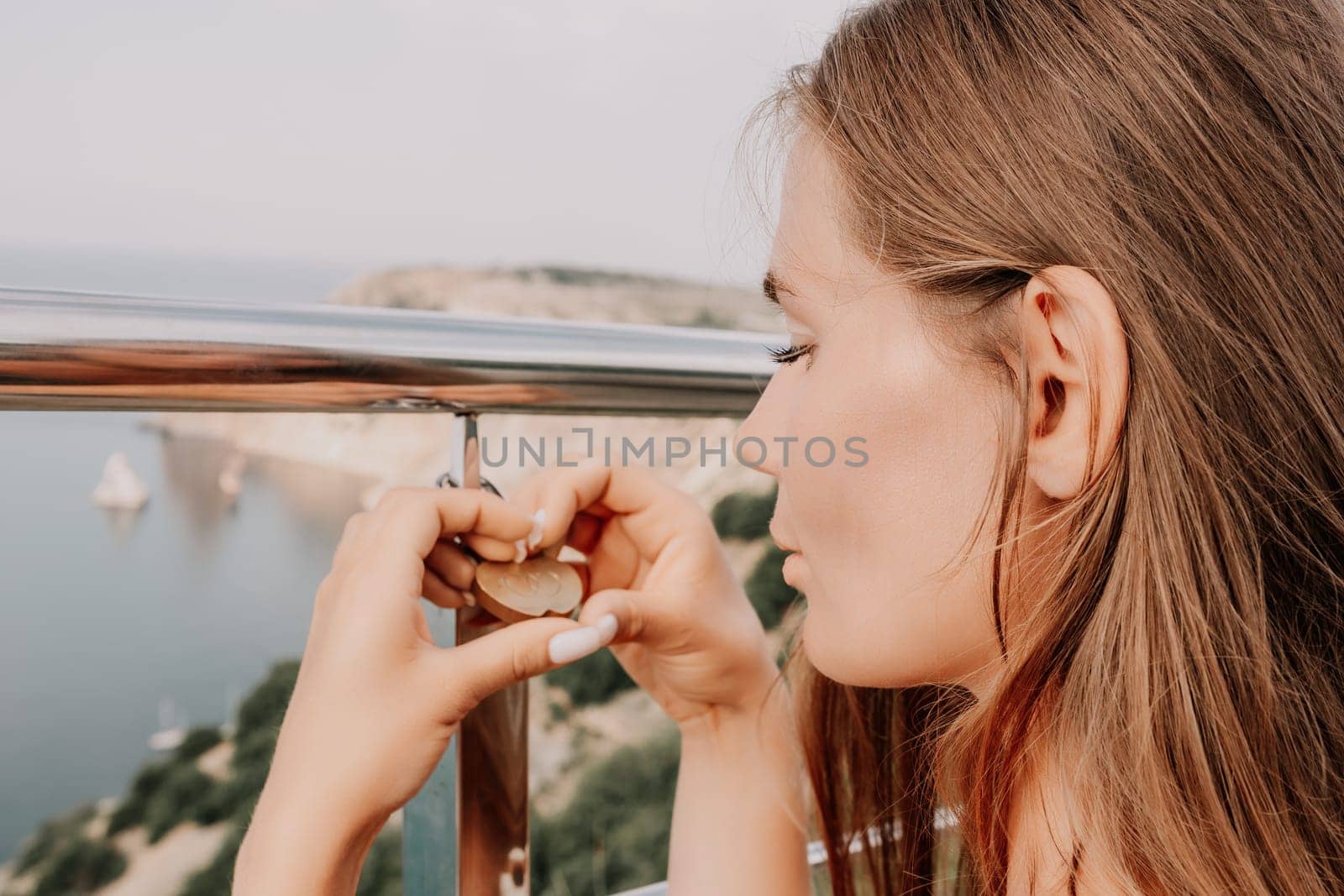 Hand, lock, heart, love, valentines day. Close up view of a woman holding a heart shaped lock that is locked onto a chain link fence.