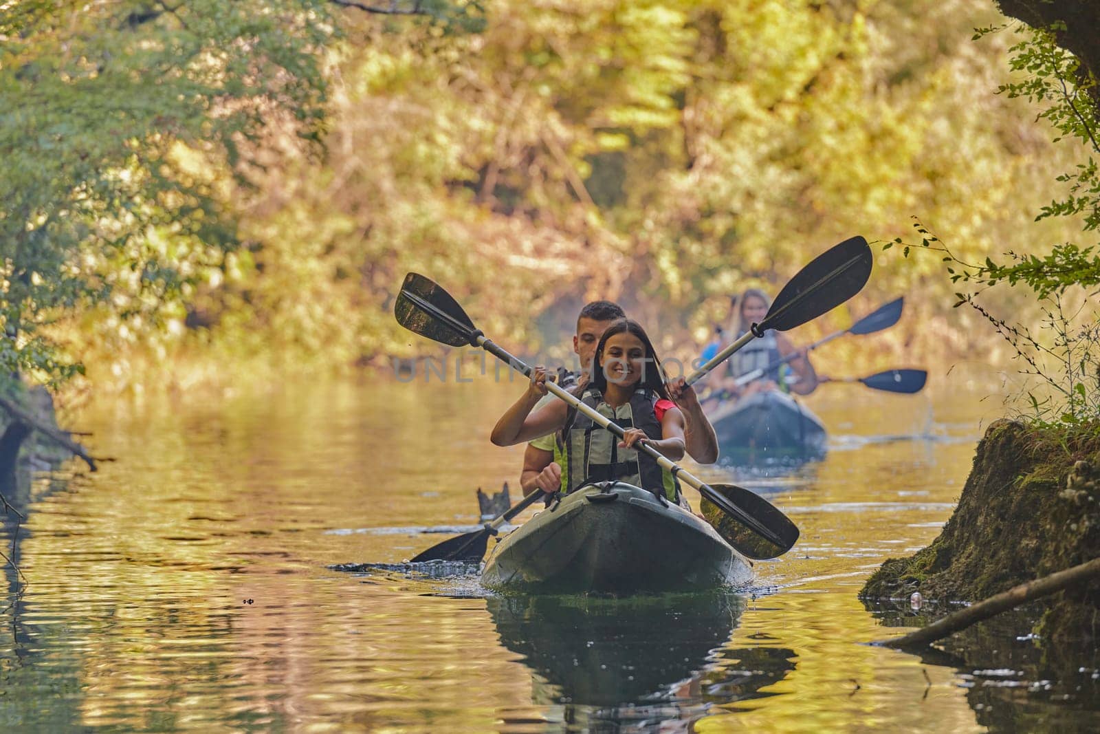 A group of friends enjoying having fun and kayaking while exploring the calm river, surrounding forest and large natural river canyons.