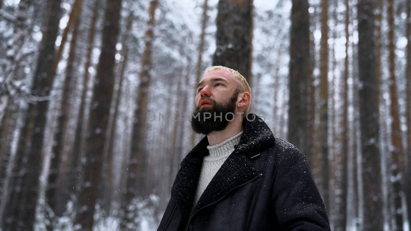 Man relaxing in the winter forest, the concept of unity with nature. Media. Young blond man thinking about life in snowy wood