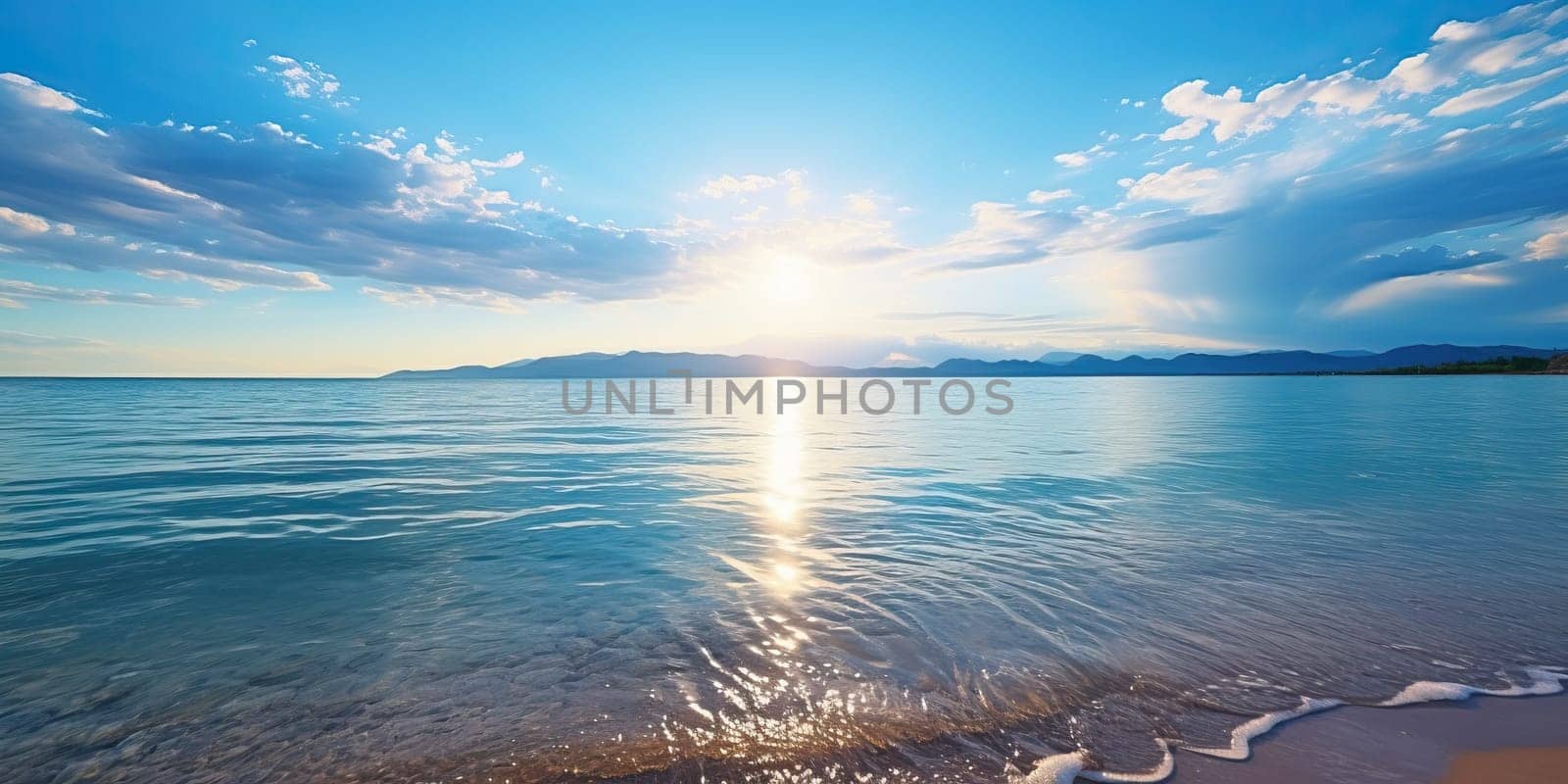 Sunset illuminating a calm sea with a sandy shore under a partly cloudy sky