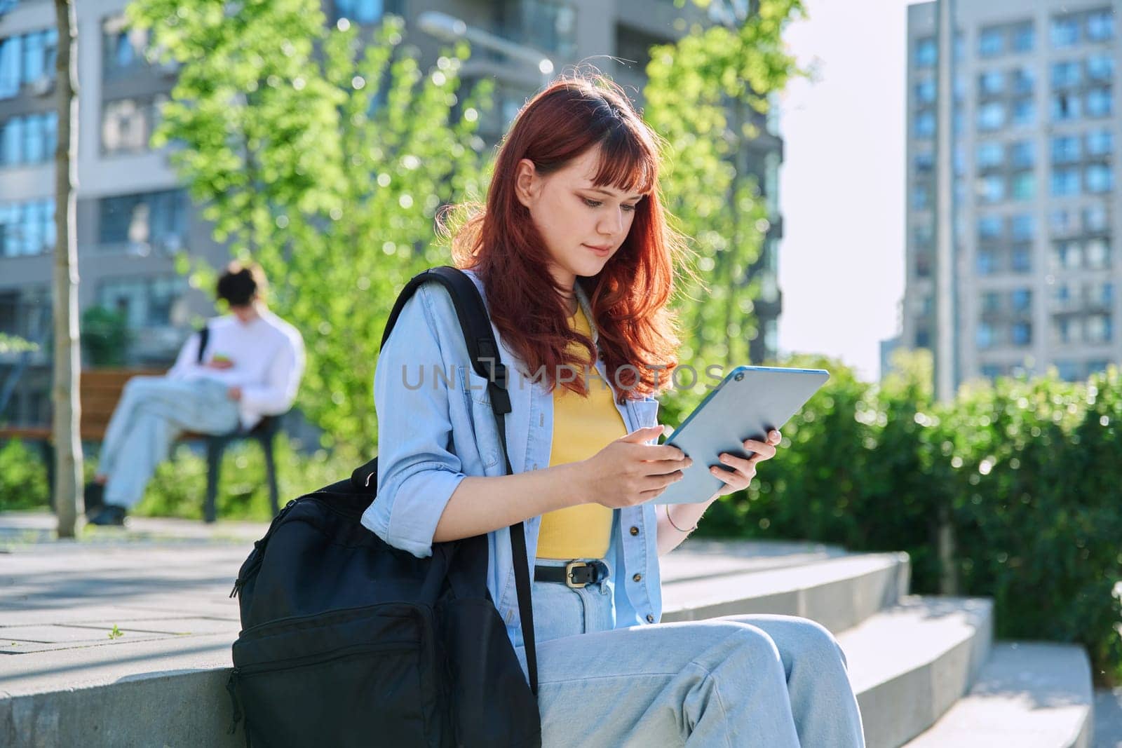 Young attractive female college student using digital tablet outdoor, educational building background. Education, technology, training, 19,20 years age youth concept