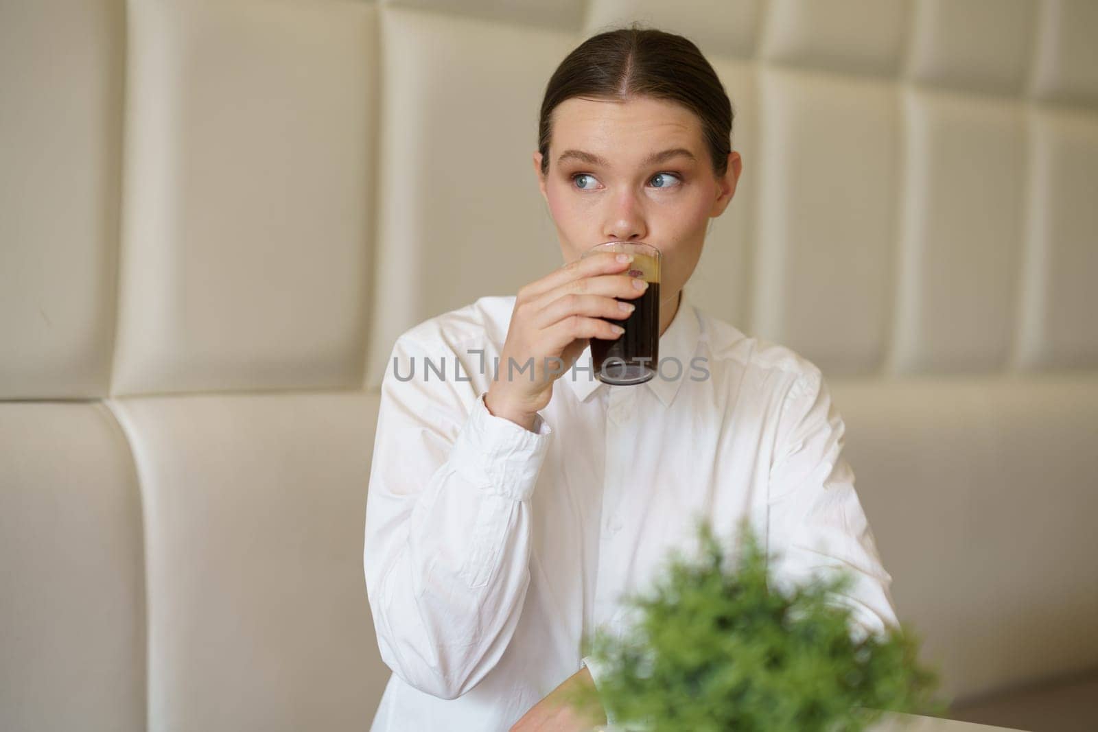 Portrait of a caucasian adult beauty woman in elegant clothes sipping black coffee in a cafeteria