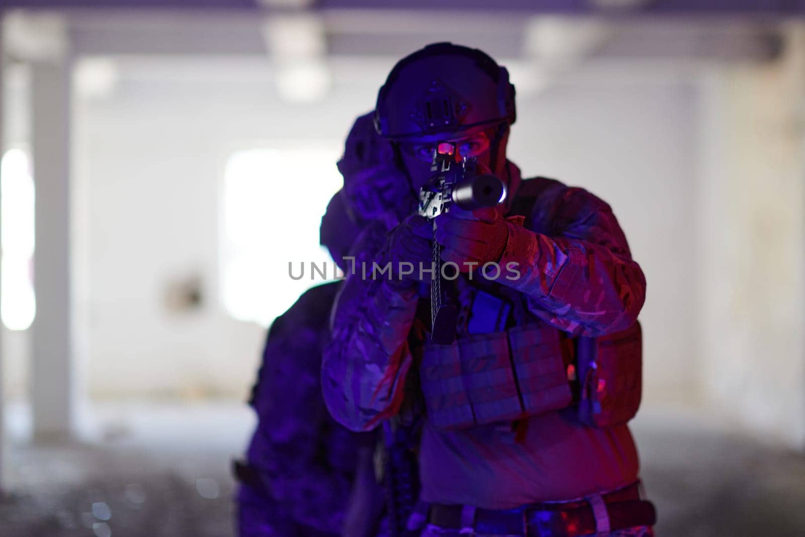 A professional soldier undertakes a perilous mission in an abandoned building illuminated by neon blue and purple lights.