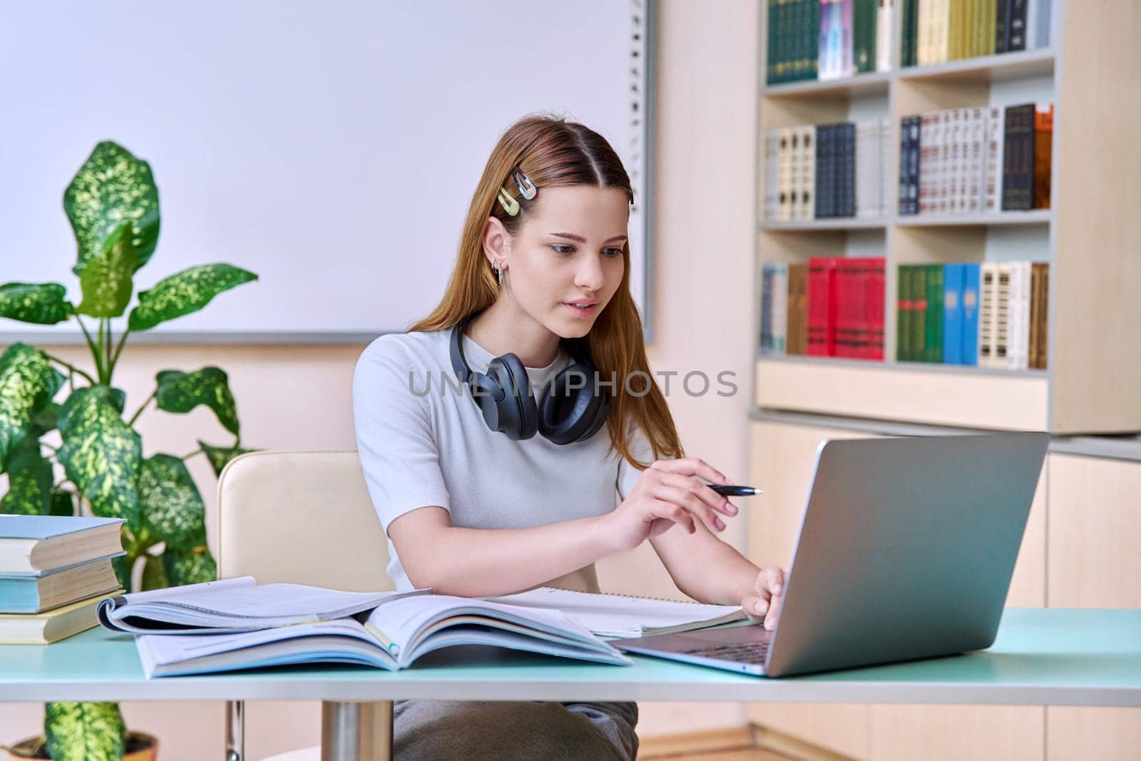 Teenage girl student studying in the high school library. Education, adolescence, knowledge concept