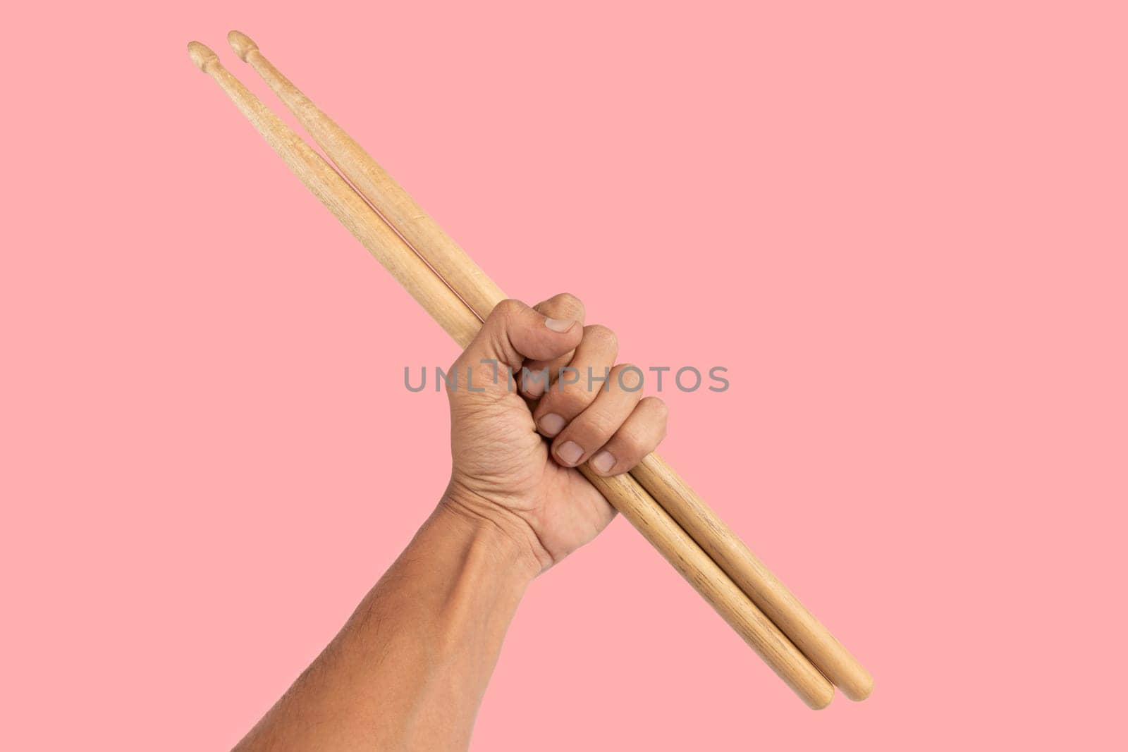 Black male hand holding wooden Drum sticks isolated on pink background. High quality photo