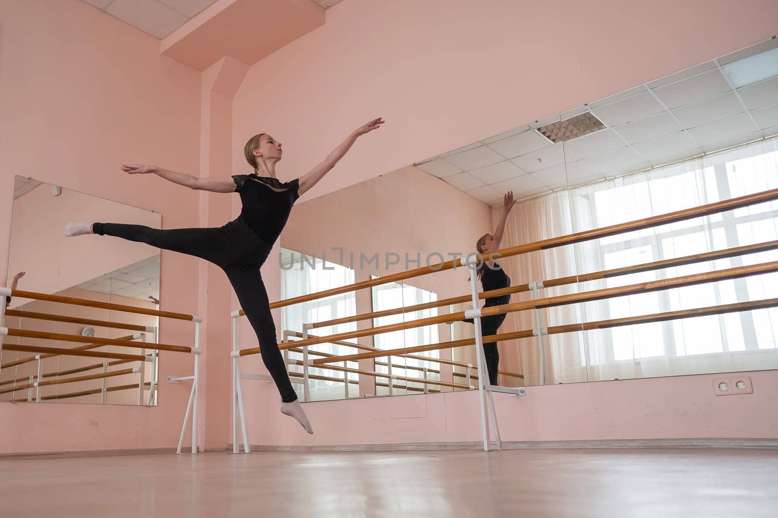 Caucasian blonde woman is practicing ballet in class. Ballerina rehearsing at the barre. by mrwed54