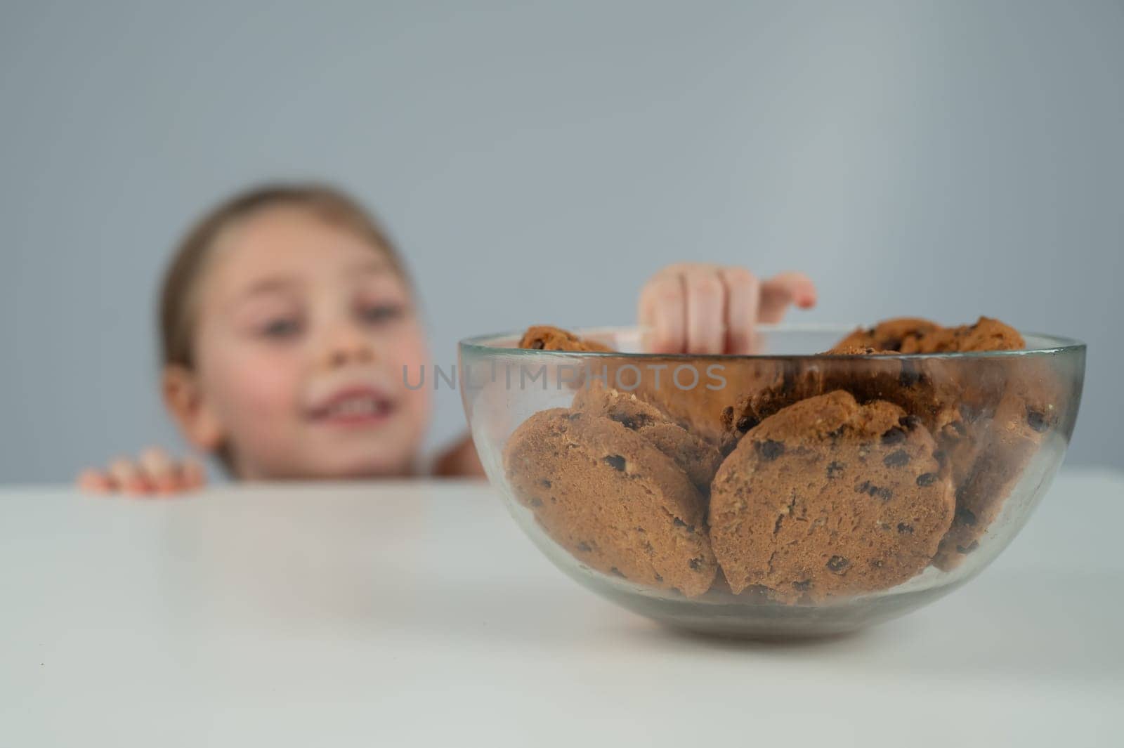 Little girl steals cookies from the table