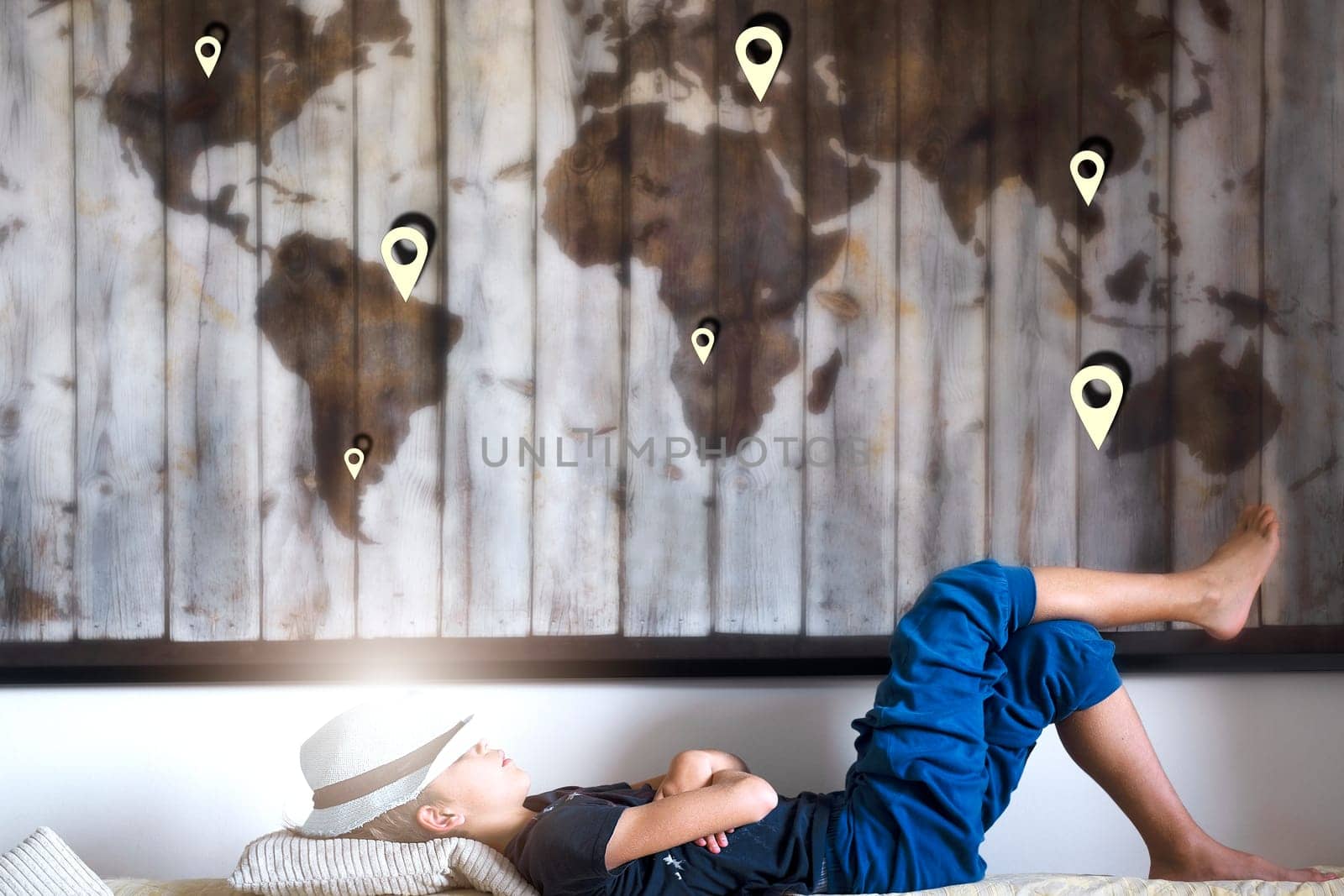 Child dreams of traveling, he lies over the map in hat and things. Travel concept by Annavish