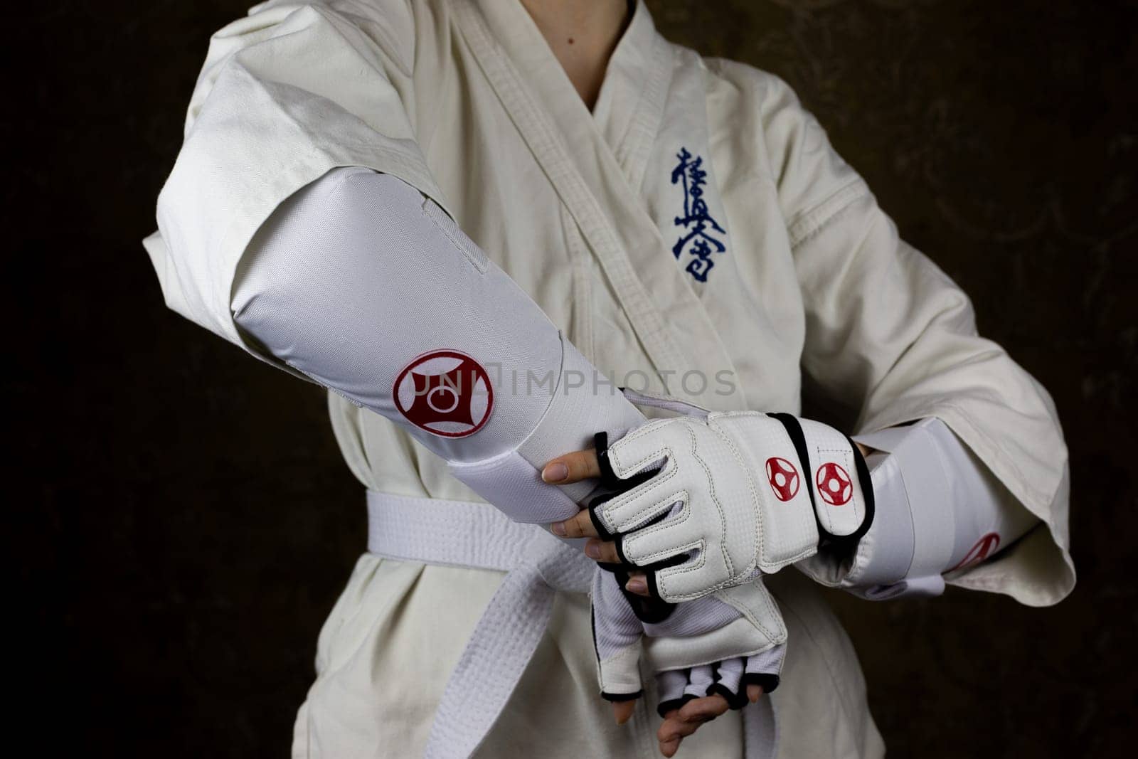 Girl in kimono and protective equipment in Kyokushinkai karate demonstrates protection on the forearm by timurmalazoniia