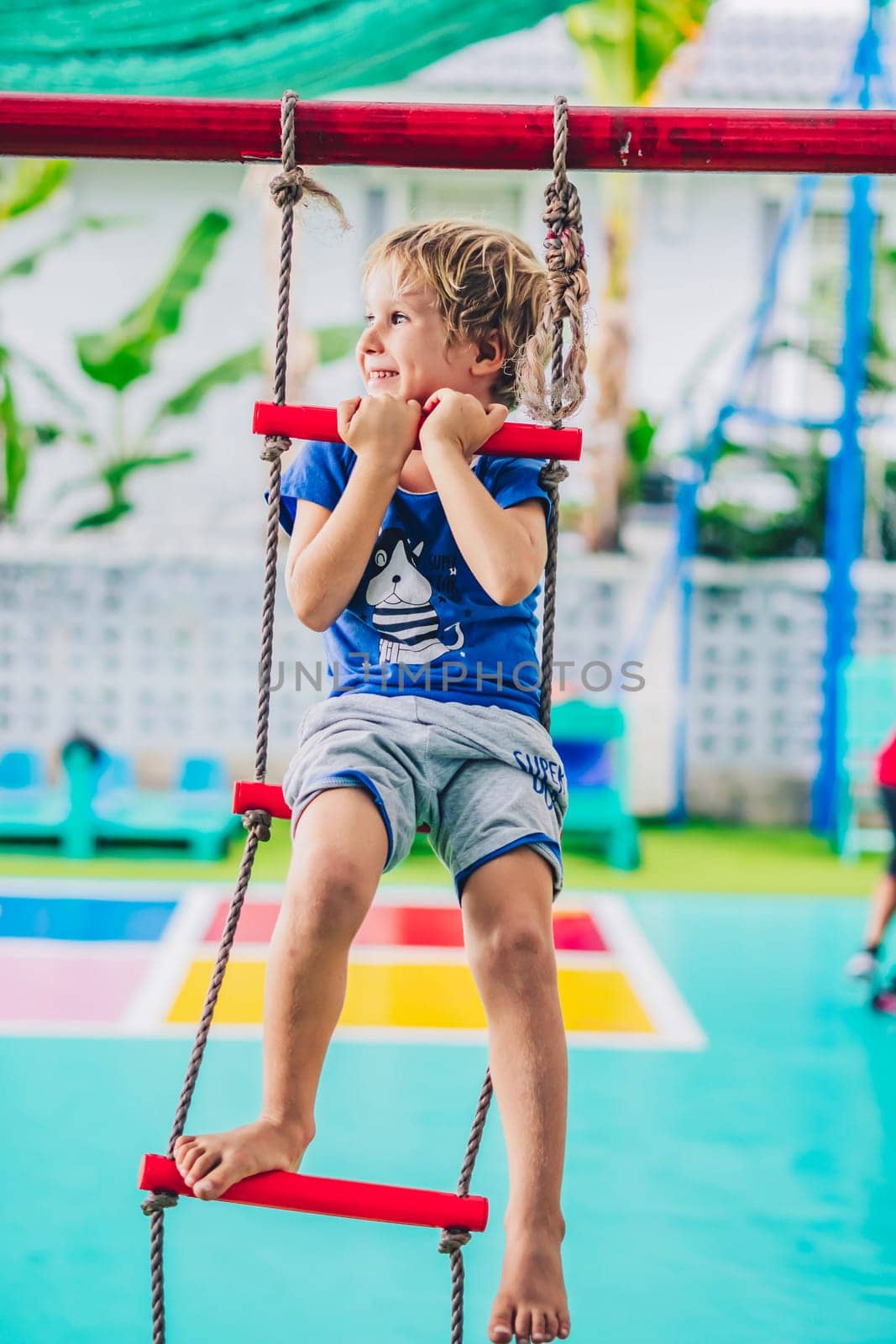 Smiling child preschool boy on rope ladder. Bright emotions. Happy childhood, enjoy life be yourself.