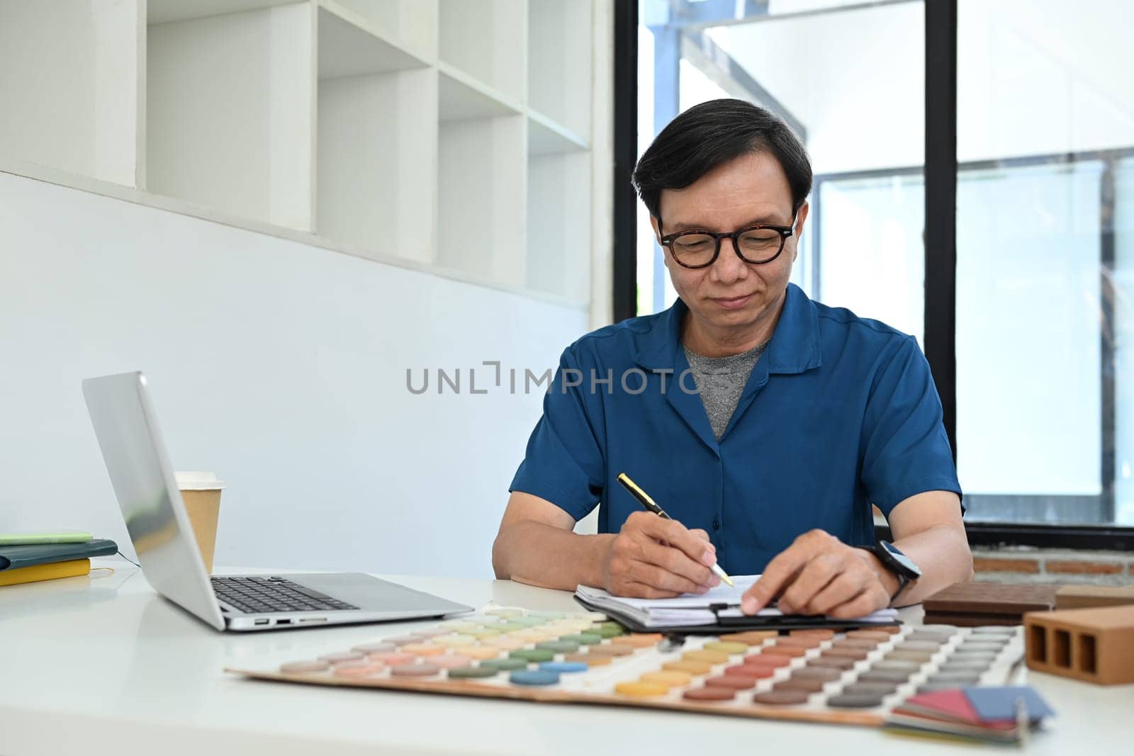 Portrait of happy senior male designer expert choosing color palette for interior architecture.