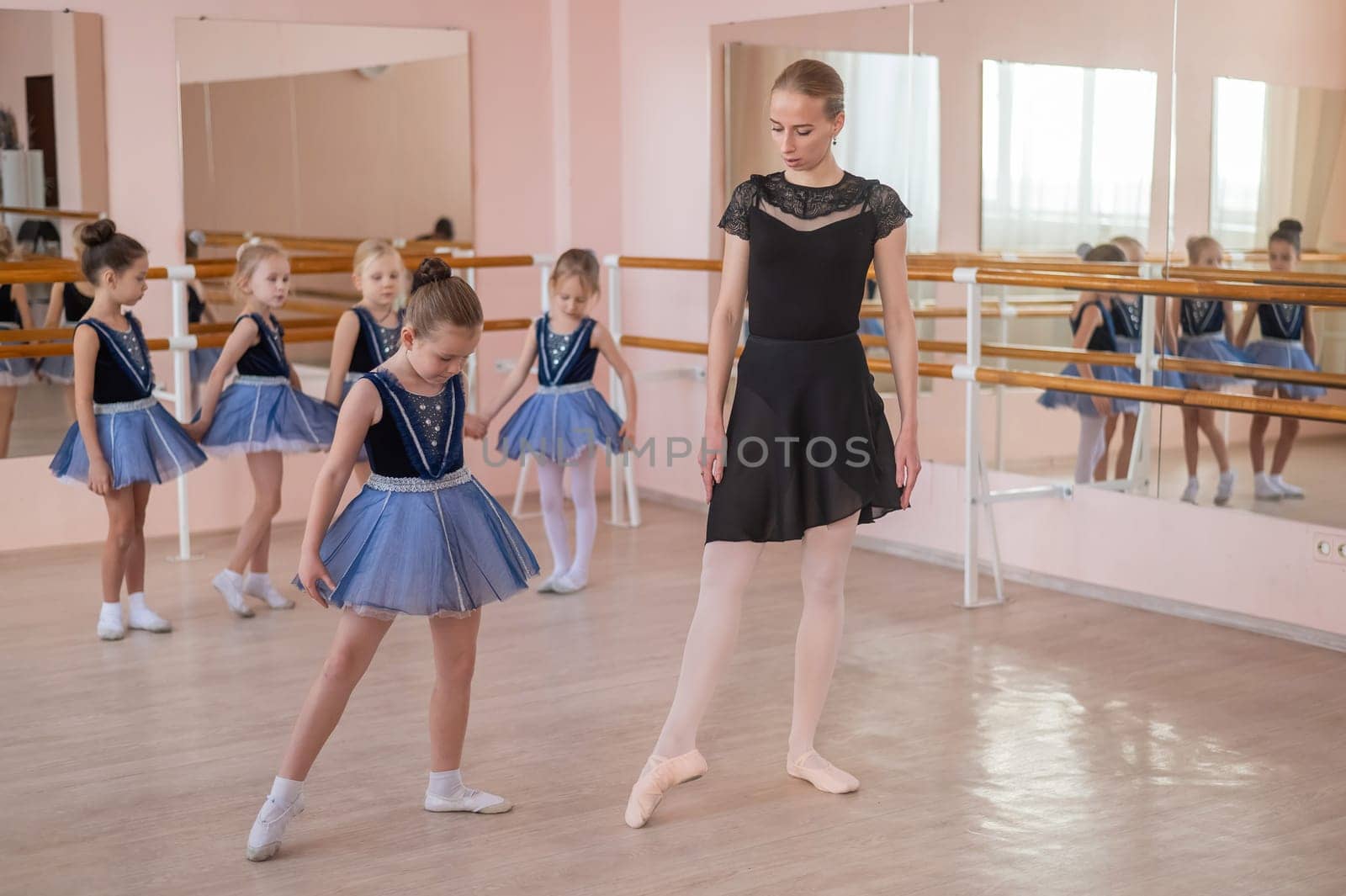 Children's ballet school. Caucasian woman teaching ballet to little girls