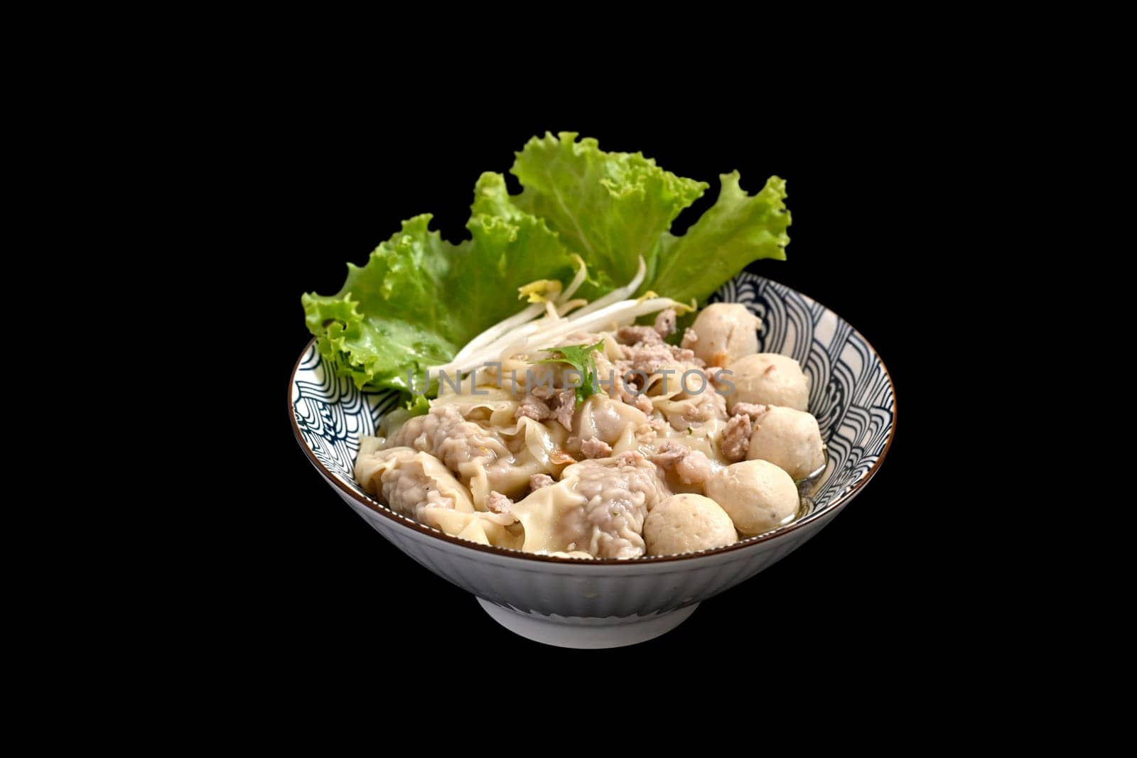 Bowl of delicious pork dumplings soup with meatballs and vegetables isolate black background.