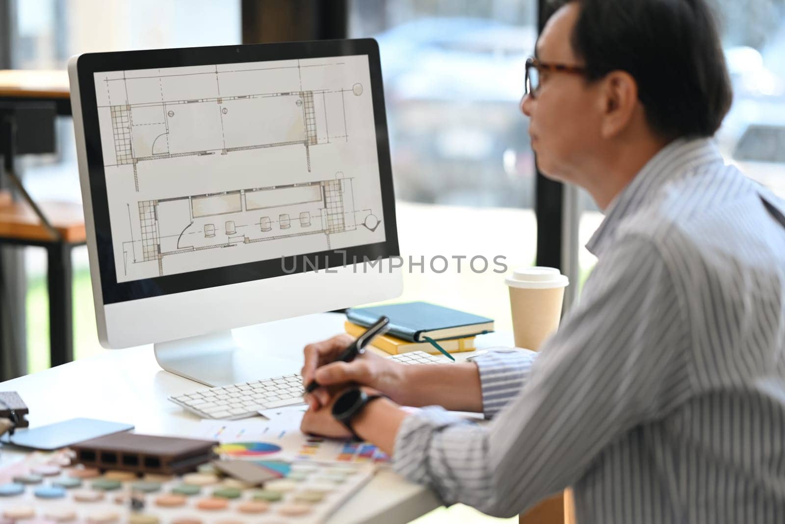Side view of experienced senior interior designer working at creative office.